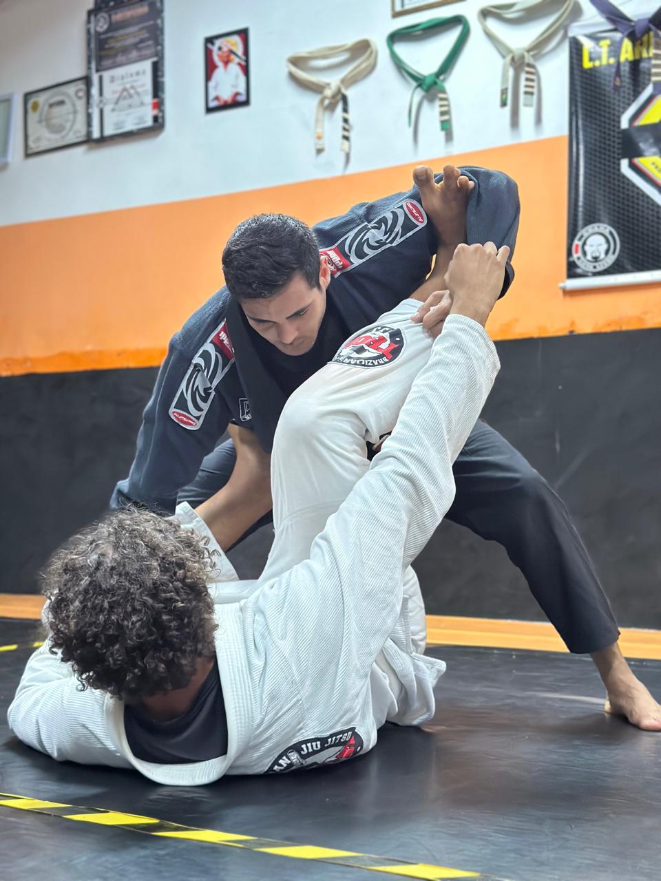 Professor aplicando técnica de Jiu-Jitsu no tatame